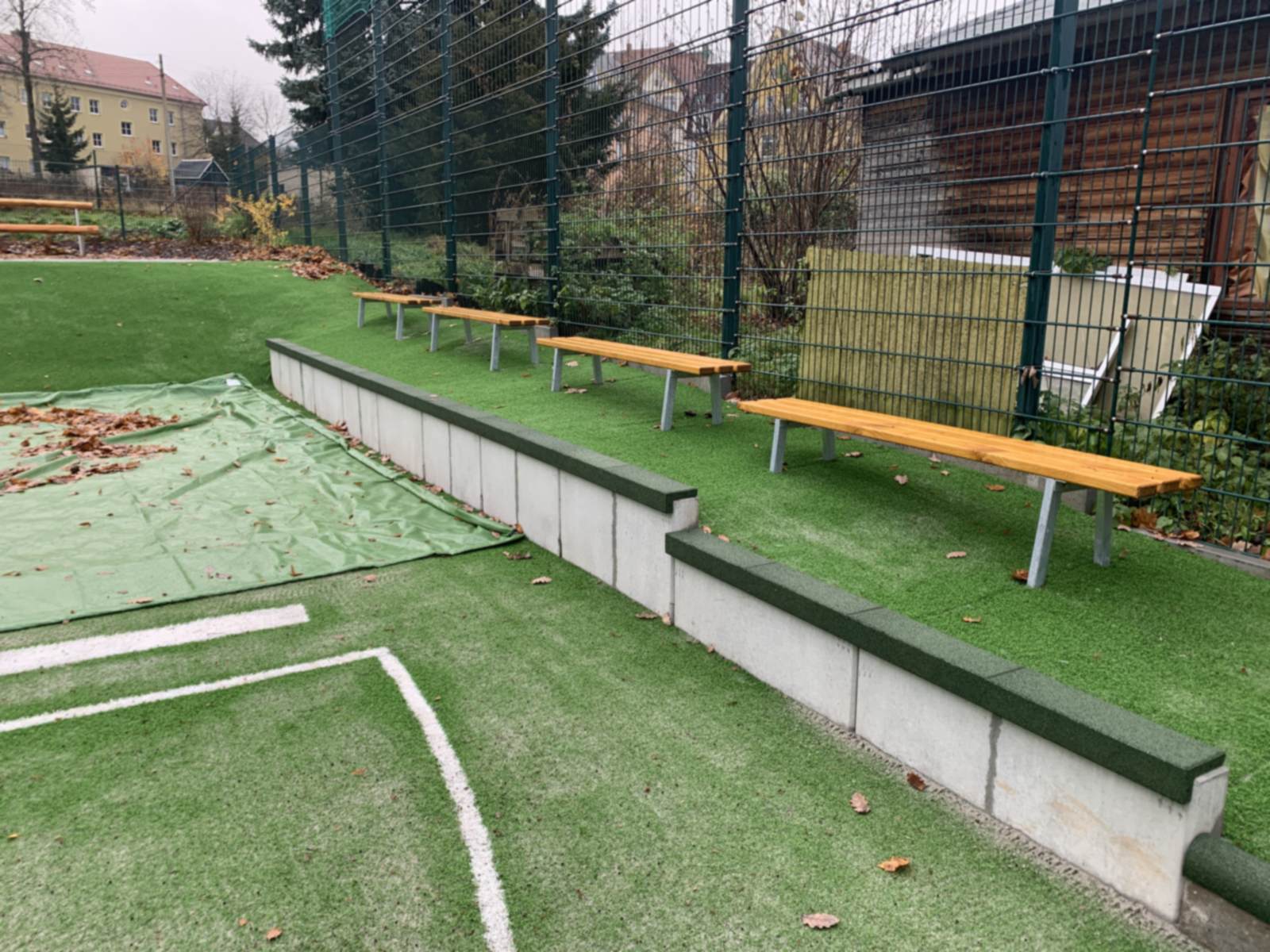 Sitzbänke aus Holz auf der Böschung über einer Betonmauer am Spielfeldrand