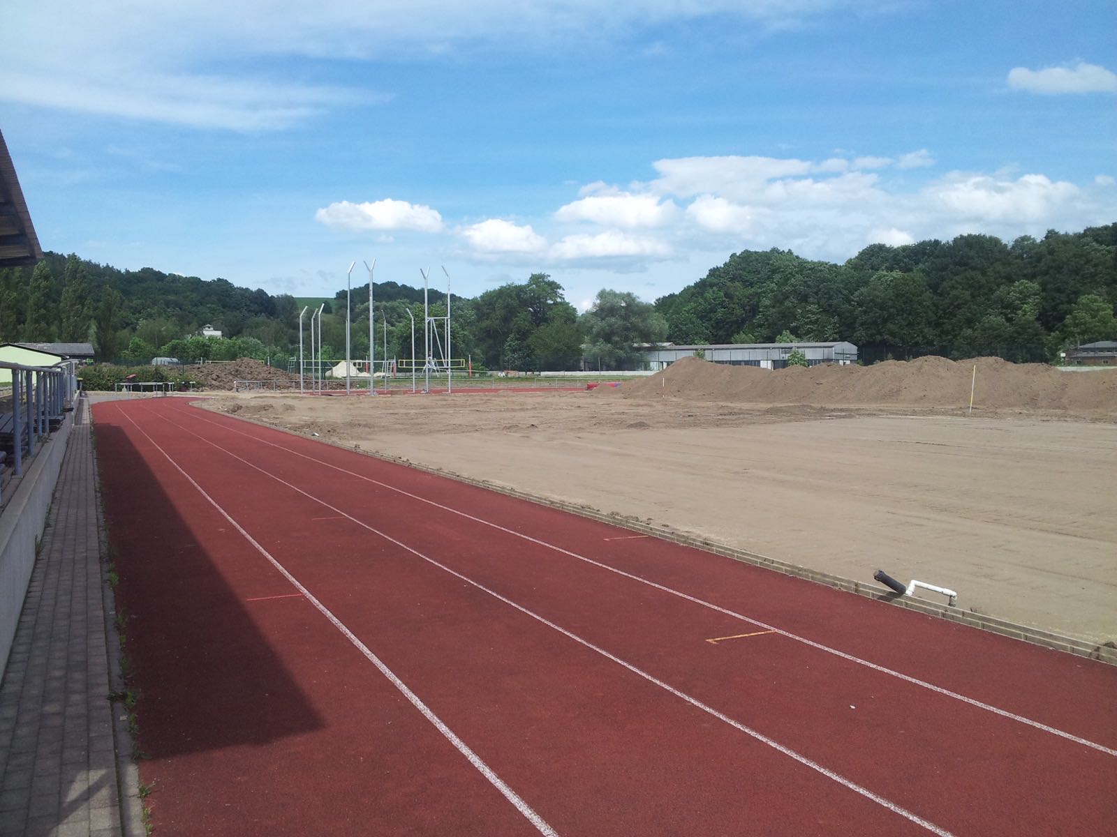 Freigelegte Spielfeldfläche neben einer roten Laufbahn im Stadion